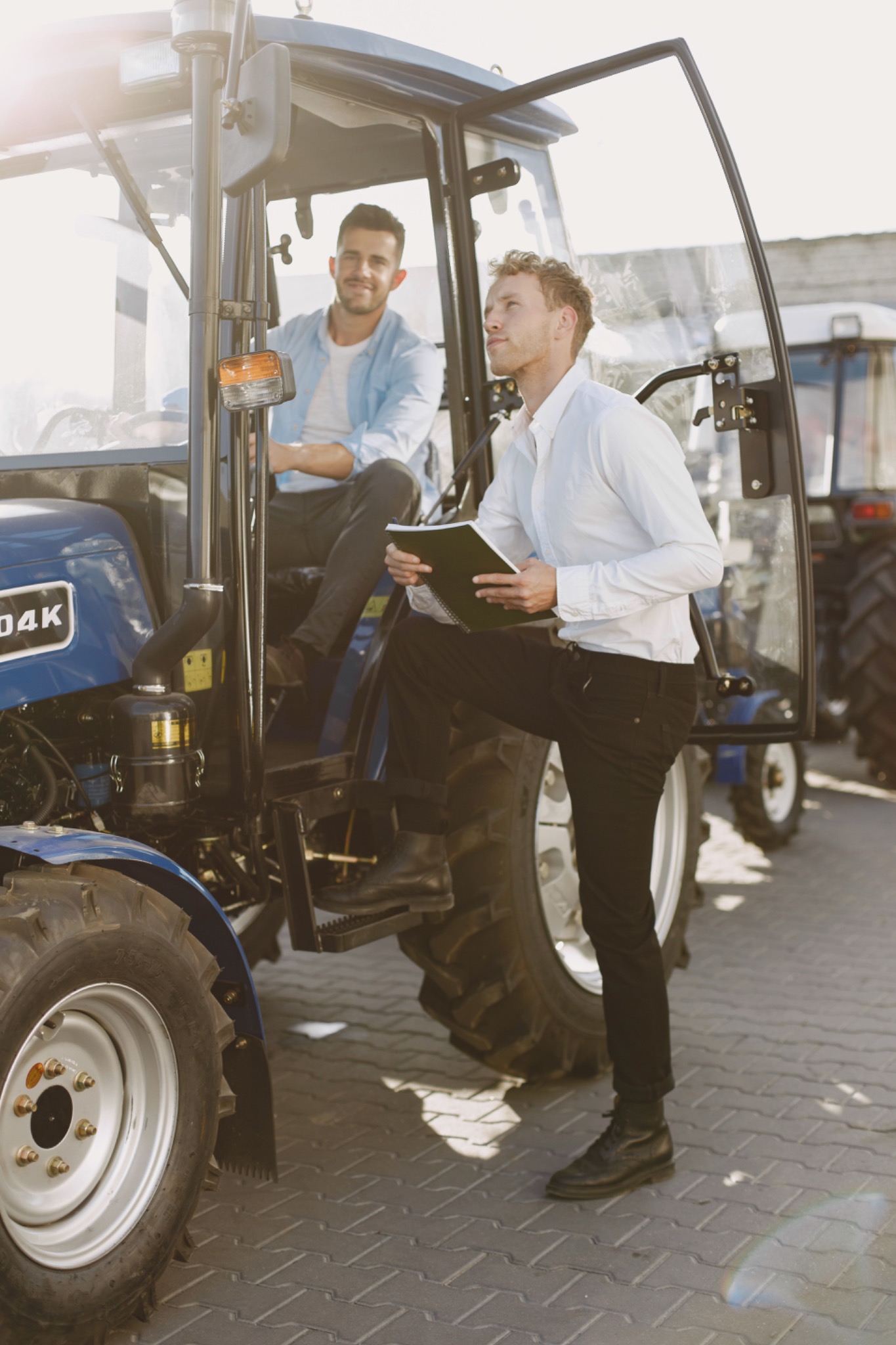 Two people discussing agricultural machinery beside a tractor